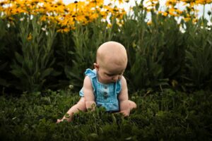 a baby sitting in a field of flowers